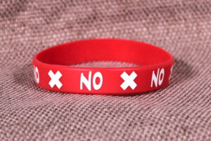 Red silicone wristband with "X NO X" printed on it.