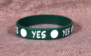 Green silicone wristband with "O YES O" printed on it.