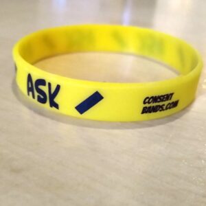 Yellow silicone "Ask" consentband showing "consentbands.com/" logotype