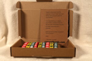 Picture of three sets of the 2nd run of Consentbands as they're shipped, wrapped around a card inside a cardboard box.